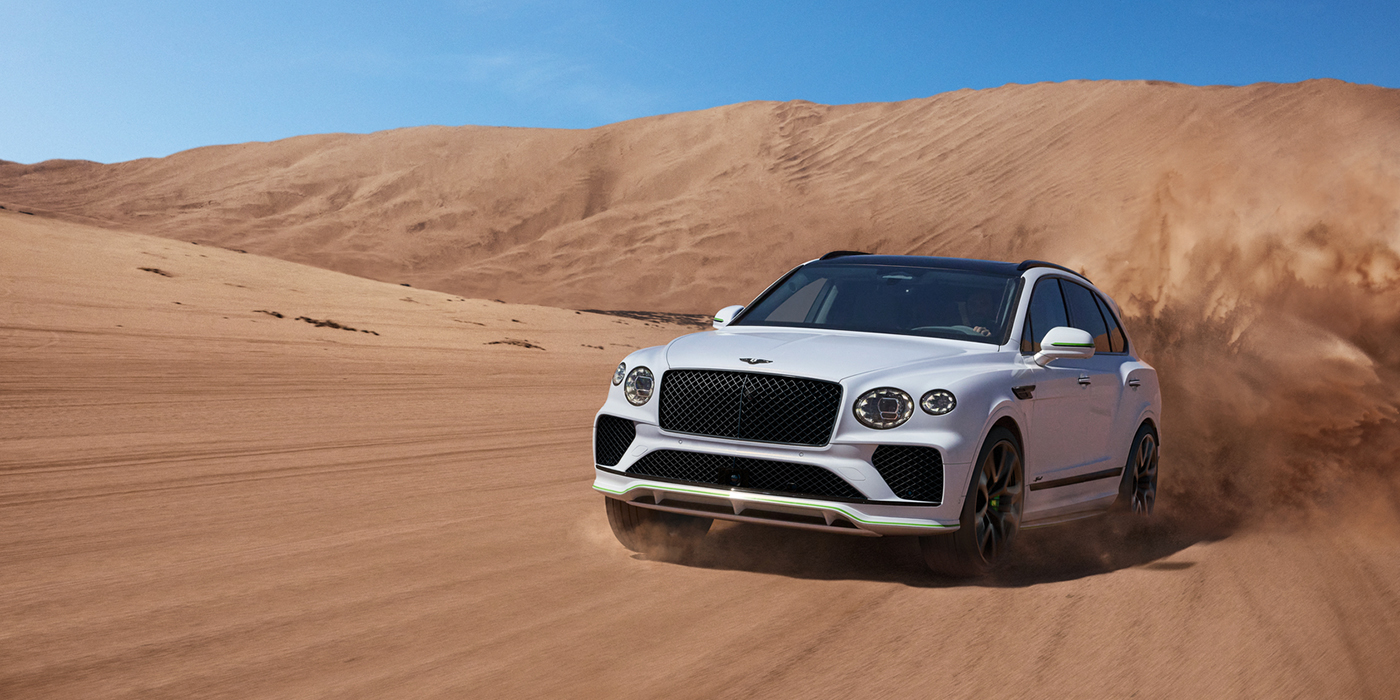 Bentley Tallinn Bentley Bentayga Speed SUV front three quarter in Snow Quarts Pearlescent by Mulliner white paint driving dynamically through the desert