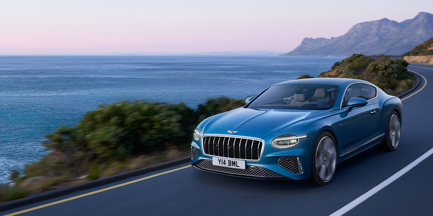 Bentley Tallinn New Bentley Continental GT Azure coupe in Light Windsor blue paint with 22 inch Azure wheels and chrome grill, driving dynamically by the sea