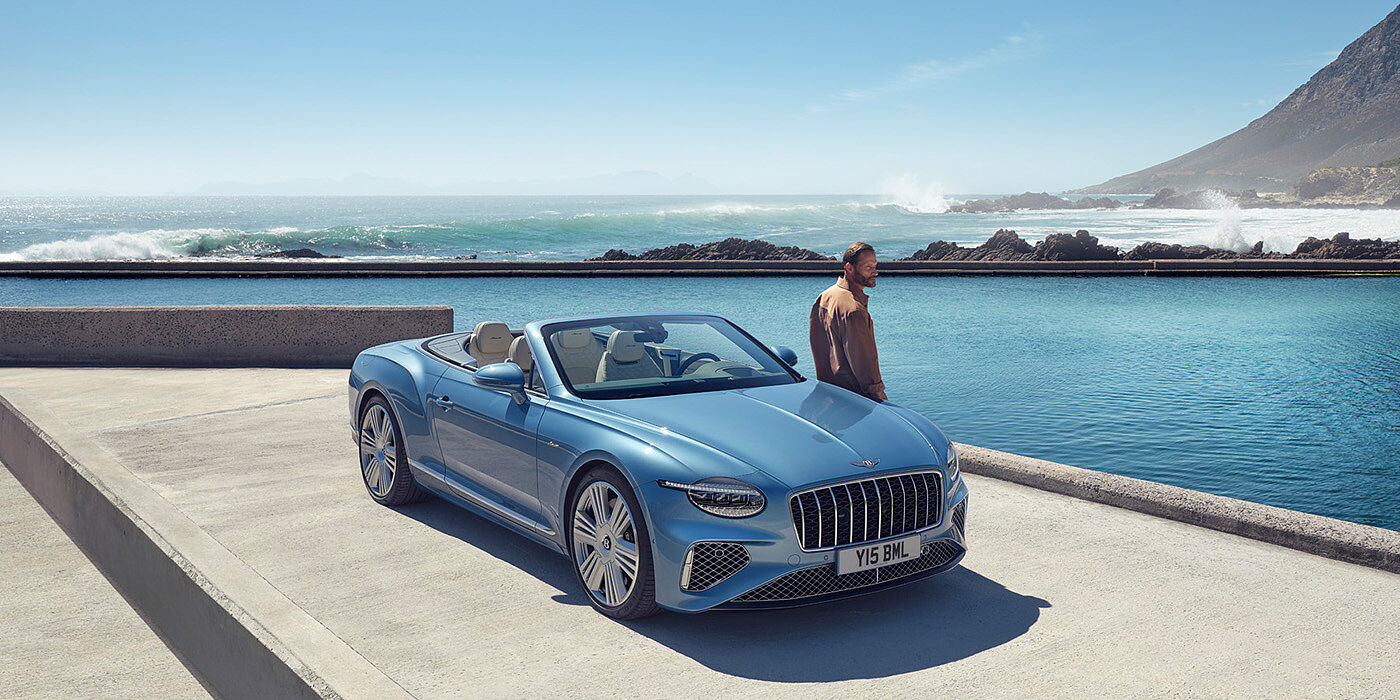 Bentley Tallinn New Bentley Continental GTC Azure convertible front view in Light Windsor blue paint with 22 inch ten spoke wheels parked by the sea in the sunshine