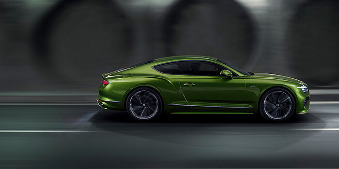  Bentley Tallinn Bentley Continental GT coupe in Tourmaline Green paint driving in profile on a dark road