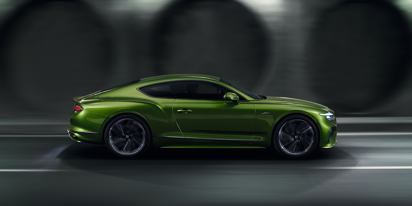 Bentley Tallinn Bentley Continental GT coupe in Tourmaline Green paint driving in profile on a dark road
