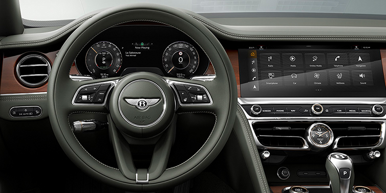 Bentley Tallinn New Bentley Flying Spur front cabin interior in Cumbrian green hide with Crown Cut walnut veneer showing steering wheel and driver controls
